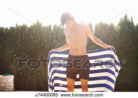 Young man drying himself with towel at poolside View Large Photo Image Stock Photography - Young man drying himself with towel at poolside. Fotosearch