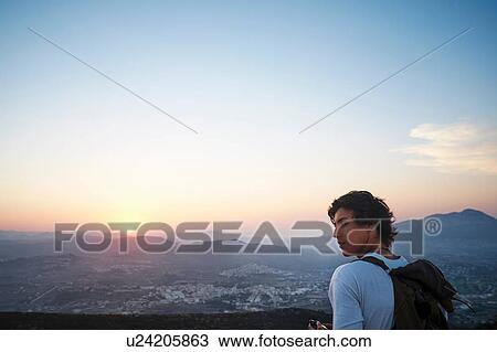 Stock Image - "Young man looking out at landscape and sunset, Javea, Spain". Fotosearch