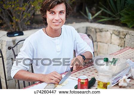 Young man slicing bread at patio table View Large Photo Image Stock Photo - Young man slicing bread at patio table. Fotosearch