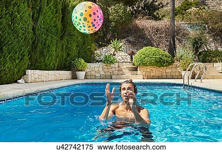 Young man throwing ball in swimming pool View Large Photo Image Stock Photography - Young man throwing ball in swimming pool. Fotosearch