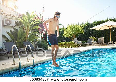 Young man wearing swimming goggles jumping into swimming pool View Large Photo Image Stock Photo - Young man wearing swimming goggles jumping into swimming pool. Fotosearch