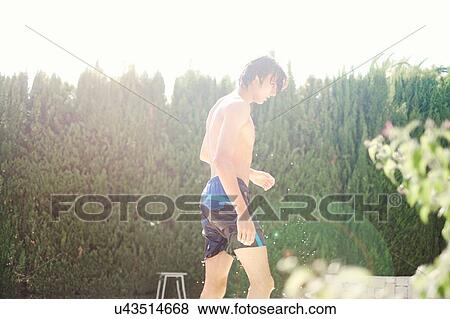 Young man wearing swimming shorts dripping wet at poolside View Large Photo Image Stock Photo - Young man wearing swimming shorts dripping wet at poolside. Fotosearch