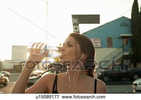 Young woman drinking water from water bottle View Large Photo Image Stock Photo - Young woman drinking water from water bottle. Fotosearch