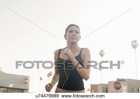 Stock Photo - Young woman jogging in street. Fotosearch