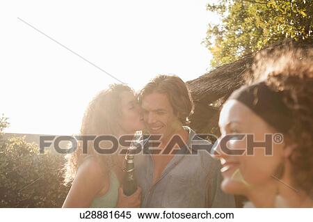 Young woman kissing mid adult man on cheek in the sunlight View Large Photo Image Stock Photography - Young woman kissing mid adult man on cheek in the sunlight. Fotosearch