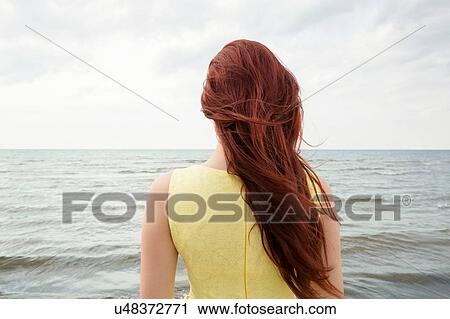 Stock Image - "Young woman on beach, rear view". Fotosearch