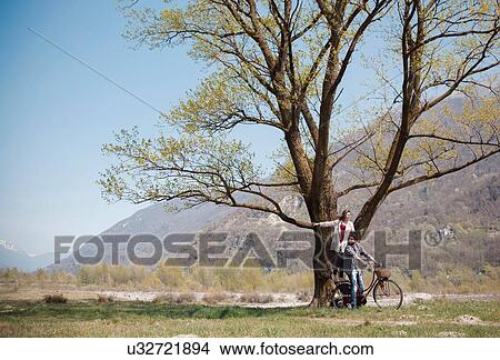 Young woman standing on bicycle behind boyfriend View Large Photo Image Picture - Young woman standing on bicycle behind boyfriend. Fotosearch