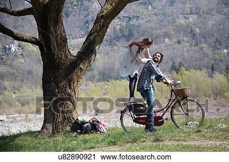 Young woman standing on bicycle behind boyfriend View Large Photo Image Stock Image - Young woman standing on bicycle behind boyfriend. Fotosearch