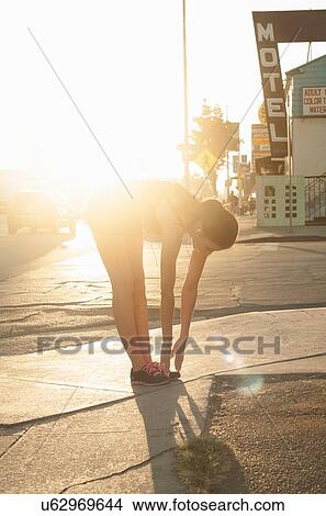 "Young woman stretching, touching toes, in street" View Large Photo Image Picture - "Young woman stretching, touching toes, in street". Fotosearch