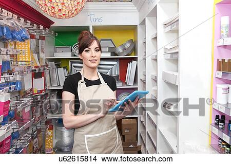 "Young woman working in cake shop, holding digital tablet, counting stock" View Large Photo Image Picture - "Young woman working in cake shop, holding digital tablet, counting stock". Fotosearch