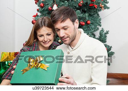 Picture - Beauty couple opening a christmas gift. Fotosearch
