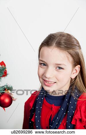 Stock Photograph - Beutiful girl standing beside the christmas tree. Fotosearch
