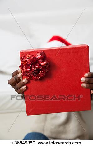 Stock Image - Black man covering his face with gift. Fotosearch