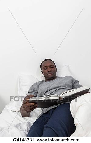 Stock Image - Black man looking at book. Fotosearch