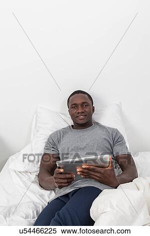 Stock Photography - Black man looking at his tablet. Fotosearch