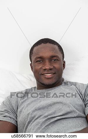 Stock Image - Black man lying in bed. Fotosearch