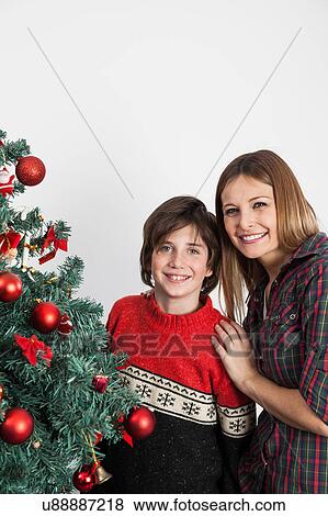 Stock Photo - Boy and his mom smiling beside the christmas tree. Fotosearch