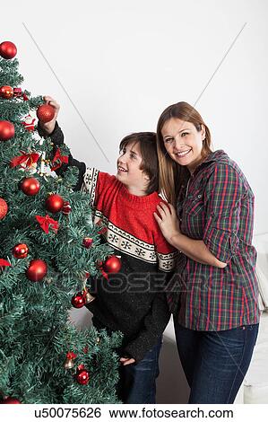 Stock Photograph - Boy and his mom smiling beside the christmas tree. Fotosearch