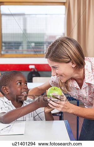 Boy giving to his teacher a apple View Large Photo Image Picture - Boy giving to his teacher a apple. Fotosearch