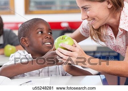 Stock Image - Boy giving to his teacher a apple. Fotosearch