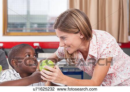 Stock Image - Boy giving to his teacher a apple. Fotosearch
