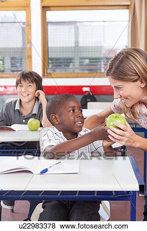 Stock Photo - Boy giving to his teacher a apple. Fotosearch