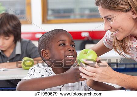 Stock Photo - Boy giving to his teacher a apple. Fotosearch