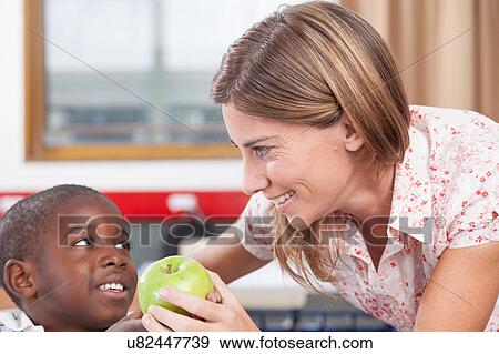Stock Photo - Boy giving to his teacher a apple. Fotosearch