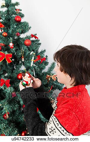 Stock Image - Boy putting ornament on Christmas tree. Fotosearch