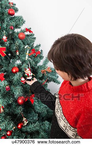Boy putting ornament on Christmas tree View Large Photo Image Stock Photograph - Boy putting ornament on Christmas tree. Fotosearch