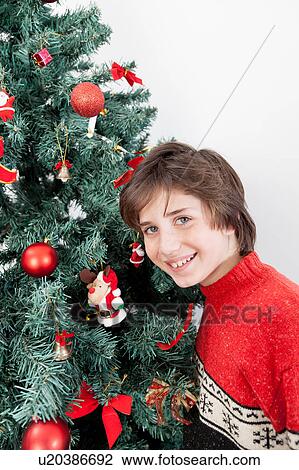 Stock Image - Boy standing beside the christmas tree. Fotosearch