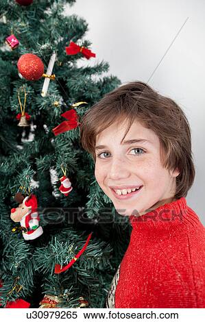 Boy standing beside the christmas tree View Large Photo Image Stock Photography - Boy standing beside the christmas tree. Fotosearch