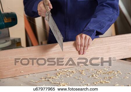 Carpenter cutting a piece ok wood View Large Photo Image Stock Photography - Carpenter cutting a piece ok wood. Fotosearch