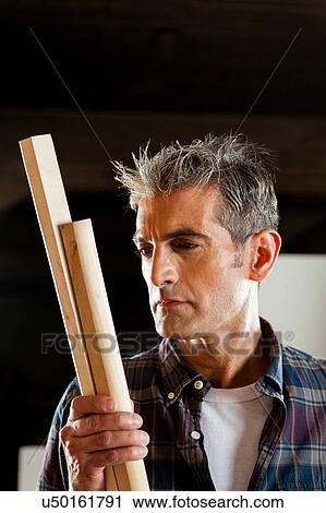 Stock Image - Carpenter looking a piece of wood. Fotosearch