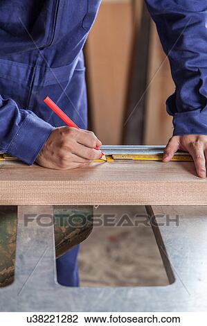 Stock Image - Carpenter marking a plank. Fotosearch