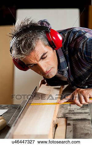 Carpenter measuring a piece of wood View Large Photo Image Stock Photo - Carpenter measuring a piece of wood. Fotosearch