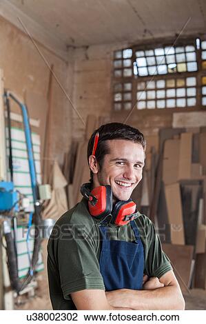Stock Image - Carpenter smiling with protectors hearing. Fotosearch