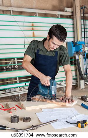 Picture - Carpenter working with a machine. Fotosearch