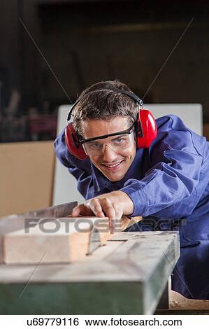 Stock Photograph - Carpenter working with a saw. Fotosearch