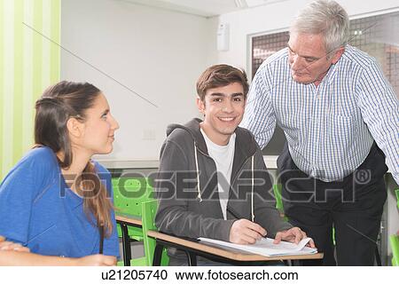 Stock Image - College teacher helps his students. Fotosearch