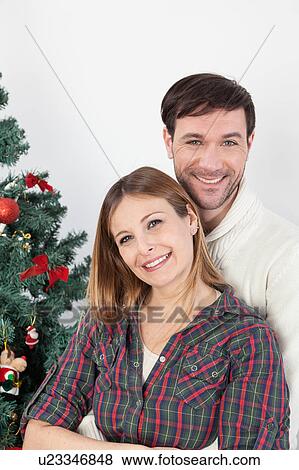 Couple hugging himself beside the christmas tree View Large Photo Image Stock Photo - Couple hugging himself beside the christmas tree. Fotosearch
