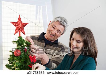 Couple putting together the christmas tree View Large Photo Image Stock Photograph - Couple putting together the christmas tree. Fotosearch