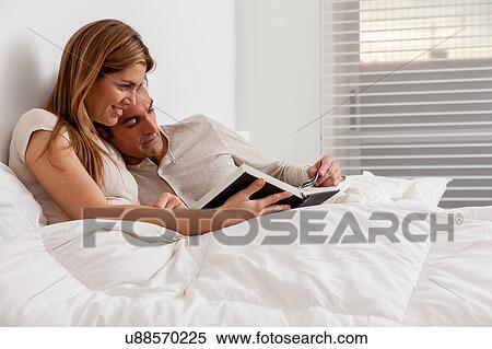 couple reading a book lying in the bed View Large Photo Image Stock Photography - couple reading a book lying in the bed. Fotosearch