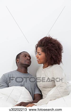 Stock Image - couple relaxing in bed. Fotosearch