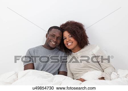 Stock Image - Couple relaxing in bed. Fotosearch