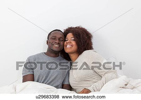 Couple relaxing in bed View Large Photo Image Stock Photo - Couple relaxing in bed. Fotosearch
