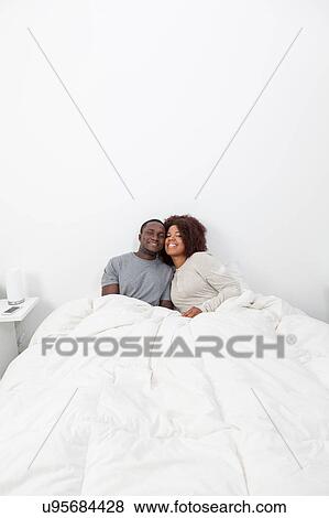 Couple relaxing in bed View Large Photo Image Stock Photo - Couple relaxing in bed. Fotosearch