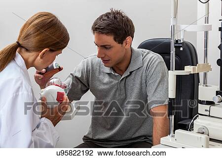 Stock Image - Doctor explaining to the patient about the eye. Fotosearch