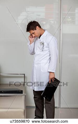 Stock Image - Doctor talking on phone. Fotosearch