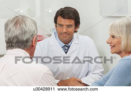 Stock Image - Elder couple visiting the doctor. Fotosearch